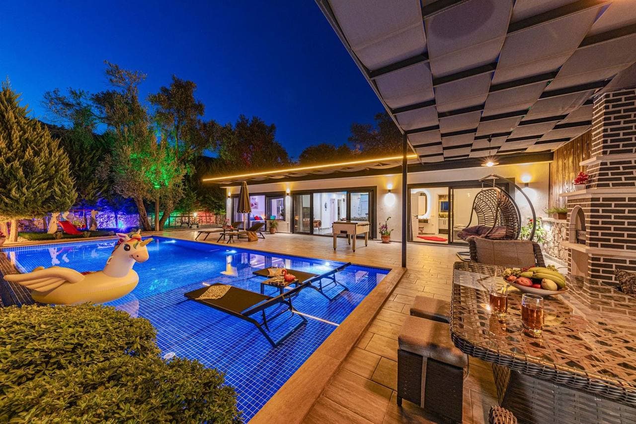 Private pool lit up at night beside a villa